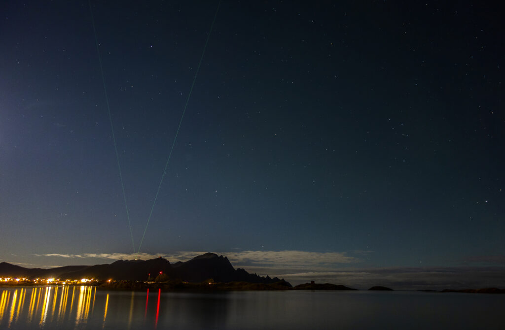 Night photo of the lidar (laser) beams in the distance. City lights. 