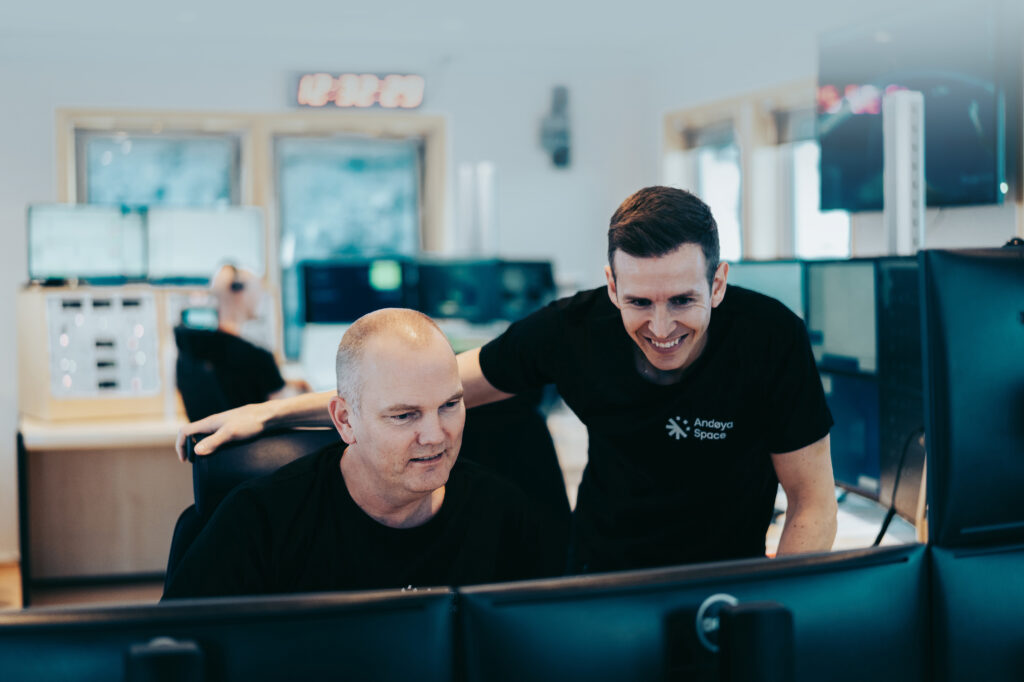 Photo of Andøya Space employees looking at computer screen and working while smiling