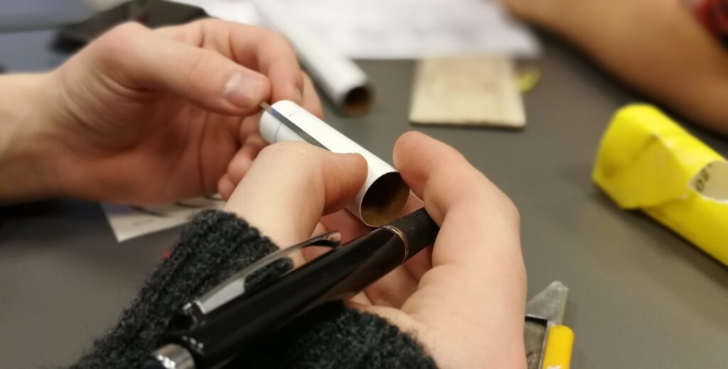 Photo of a pair of hands creating a paper rocket.